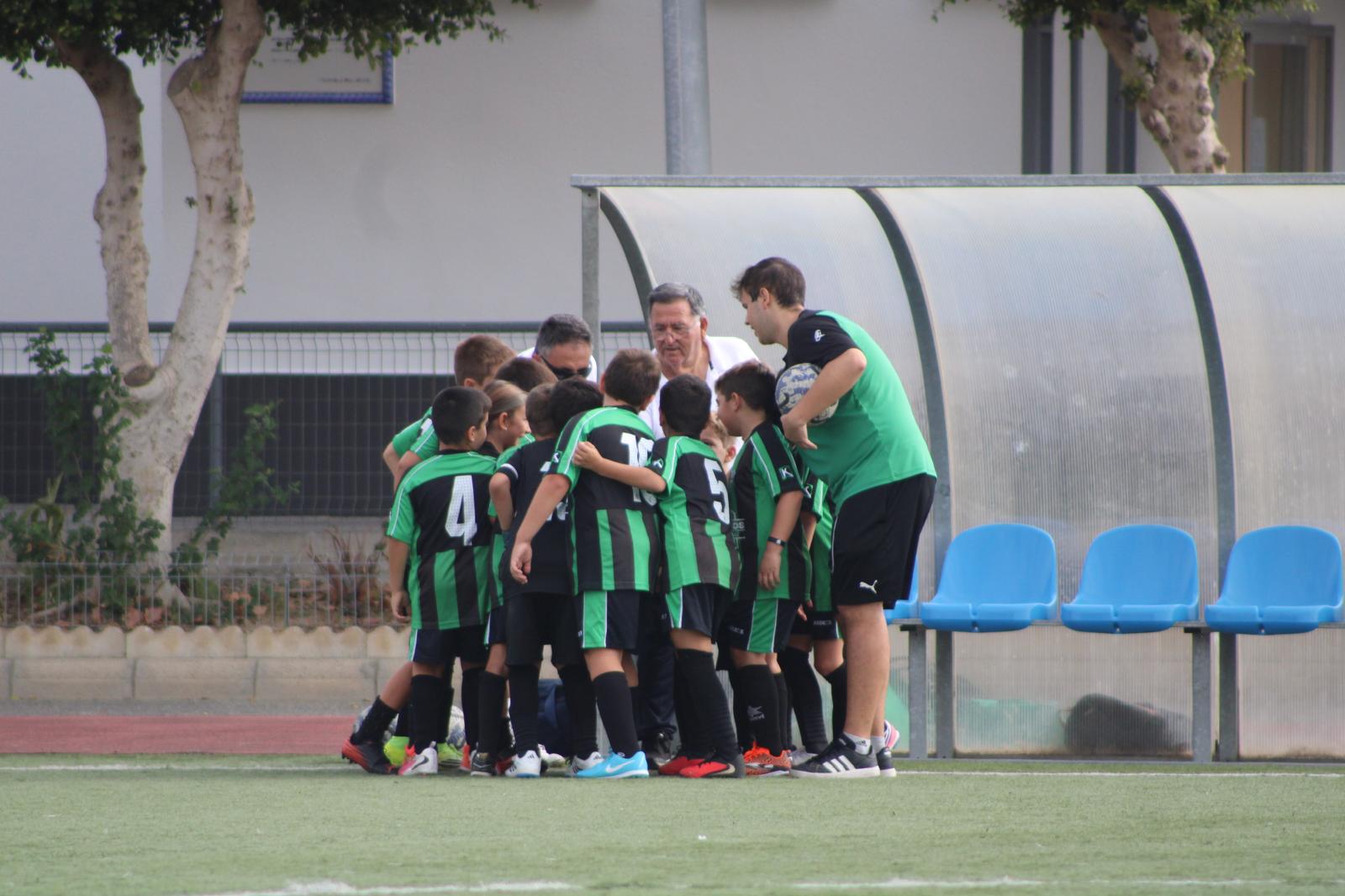 Jugadores del Benjamín del Sporting reunidos con los técnicos junto al banquillo
